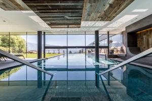 una piscina coperta con pavimenti in vetro e pareti in vetro di Avidea - Adults Only a Lagundo