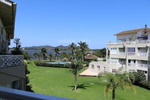 uma vista para um edifício e um quintal com palmeiras em Completo apartamento em Resort na beira da lagoa em Florianópolis