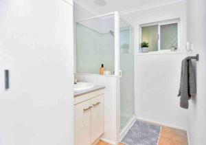 a white bathroom with a shower and a sink at Island Villas - Lady Musgrave - Unit 1 in Bundaberg