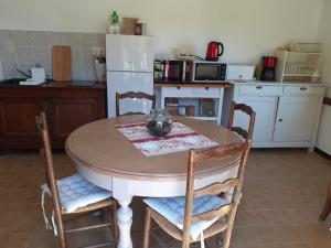 a kitchen with a table with chairs and a refrigerator at Gîte du Petit Bois 2/5 pers in Le Buisson de Cadouin