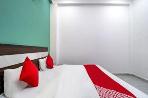 a bedroom with a white bed with red pillows at OYO 71370 White House in Garhi Harsāru
