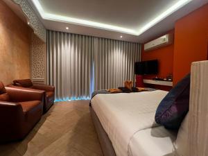 a bedroom with a bed and a couch and a chair at Le Maroc Hotel Patong in Patong Beach