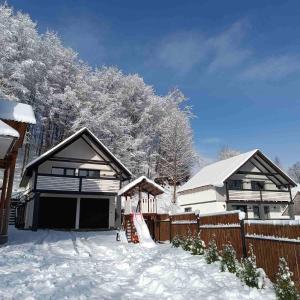 a house is covered in snow with a fence at Family House in Izki