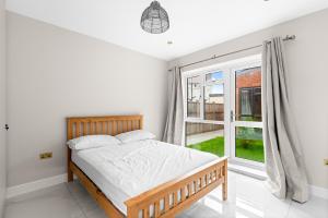 a bedroom with a bed and a large window at Stylish Sparkling Brand New 2 bed house in Heston