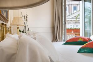 una camera da letto con un letto con cuscini bianchi e una finestra di Grand Hotel Plaza a Roma