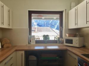 una cocina con microondas y una ventana con nieve en Fewo Karwendelglühen, en Mittenwald