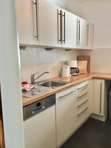 a kitchen with white cabinets and a sink at Fewo Karwendelglühen in Mittenwald