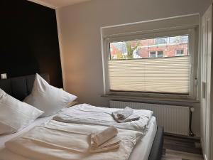 uma cama num quarto com uma janela com uma toalha em Ferienwohnung Ant Dopke em Krummhörn