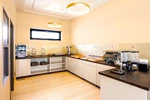 a kitchen with white cabinets and a black counter top at Ikonik Spa Hotel in Nyíregyháza