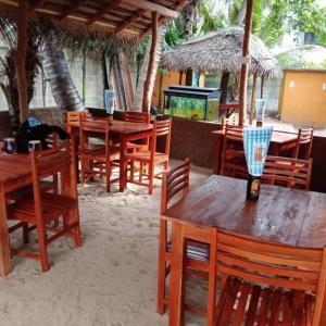 un grupo de mesas y sillas de madera en un restaurante en MENAKA HOMESTAY en Tangalle
