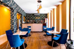 ein Restaurant mit blauen Stühlen und Tischen und eine Bar in der Unterkunft Ikonik Spa Hotel in Nyíregyháza