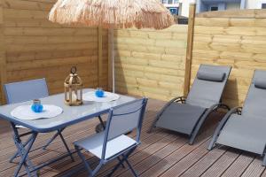 einen Tisch und Stühle auf einer Terrasse mit einem Sonnenschirm in der Unterkunft "La Mer Bohème", patio, parking privé, 8 mn plage in Le Portel