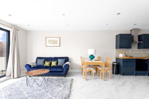 Stylish Sparkling Brand New 3 bed house في Heston: غرفة معيشة مع أريكة زرقاء وطاولة