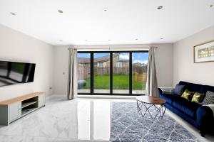 Stylish Sparkling Brand New 3 bed house في Heston: غرفة معيشة مع أريكة زرقاء وتلفزيون