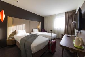 pokój hotelowy z dwoma łóżkami i walizką w obiekcie Campanile Le Mans Centre - Gare w mieście Le Mans