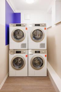 three washing machines are stacked in a laundry room at POHA House Büchel in Aachen