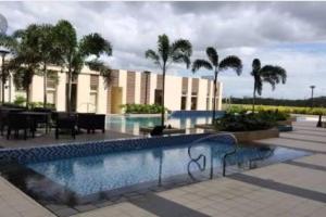 a swimming pool with palm trees and a building at Abl@home in Angeles