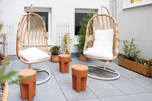 two wicker chairs sitting on a patio with plants at POHA House Büchel in Aachen