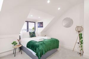 a white bedroom with a bed with a green blanket at Chic 4 person penthouse & views West London W7 Modern free parking (4 occupancy) in London