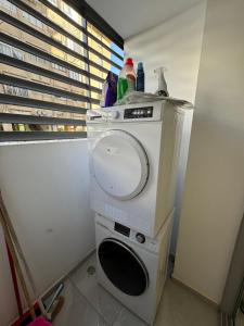 eine Waschmaschine und einen Trockner in einem Zimmer mit Fenster in der Unterkunft האצ״ל 1 in Aschdod