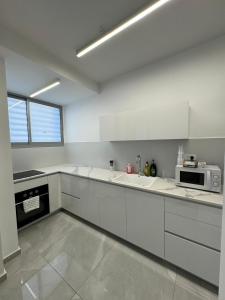 a kitchen with white cabinets and a microwave at האצ״ל 1 in Ashdod