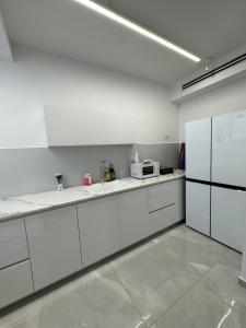 a white kitchen with a sink and a microwave at האצ״ל 1 in Ashdod