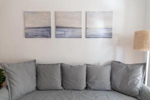 un sofá en una sala de estar con 3 pinturas en la pared en Alta Mar by Gades Gestión, en Cádiz