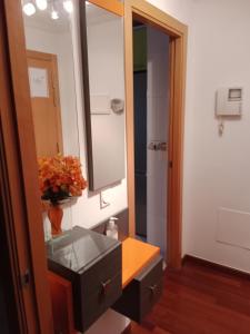 a bathroom with a sink and a mirror and a vase of flowers at La casita de Miguel, con garaje y piscina in Zamora