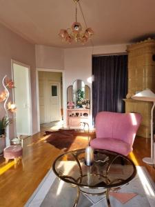 a living room with a pink chair and a glass table at Lovely Vintage Suite in Helsinki