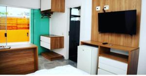 a room with a tv and a desk with a television at HOTEL ENSEADA BEIRA MAR in Guarujá
