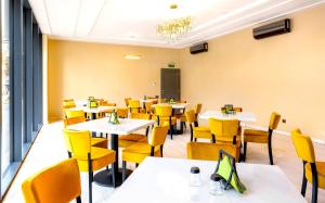 a dining room with tables and yellow chairs at Ikonik Spa Hotel in Nyíregyháza