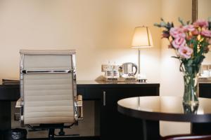 a room with a table and a chair and a vase of flowers at Paris Hotel Yerevan in Yerevan