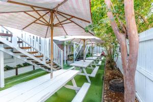 eine Reihe von Picknicktischen mit Sonnenschirmen auf einer Terrasse in der Unterkunft Surf Inn Boutique Backpackers - FREE BREAKFAST in Gold Coast