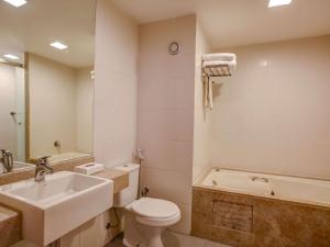 a bathroom with a sink and a toilet and a tub at Novotel RJ Santos Dumont in Rio de Janeiro