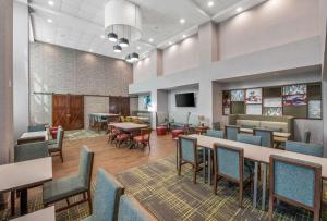 Hampton Inn & Suites Dallas-Allen في ألين: غرفة انتظار كبيرة مع طاولات وكراسي