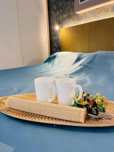 zwei Kaffeetassen und ein Tablett mit Essen auf dem Bett in der Unterkunft La Dolce Vita Penthouse 2 Bedroom Apartment in Arona