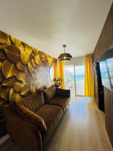 a living room with a brown couch in front of a stone wall at La Dolce Vita Penthouse 2 Bedroom Apartment in Arona