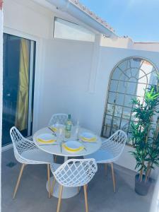 une table et des chaises blanches dans une chambre avec fenêtres dans l'établissement La Dolce Vita Penthouse 2 Bedroom Apartment, à Arona