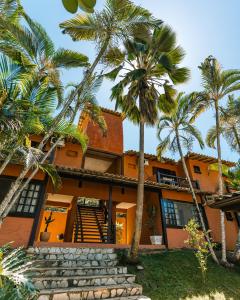 an orange house with palm trees in front of it at Pousada Casa Cactus Praia da Tartaruga Búzios in Búzios