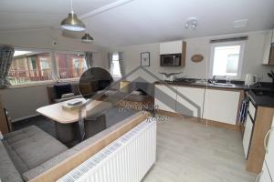 a kitchen and a living room with a table and a couch at Serenity - 8 Berth 3 Bedroom Static Caravan in Heysham