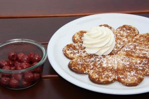a plate of waffles with whipped cream and a bowl of berries at Hotel-Restaurant Haus Berkenbaum in Kierspe