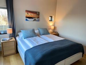 a bedroom with a bed with blue sheets and a window at Bakki and Holt in Borgarnes
