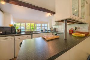 a kitchen with a black counter top with a microwave at Damson Cottage - Chocolate Box Cottage in Crook, near Bowness in Crook