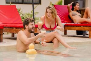 a man and woman sitting in a swimming pool with glasses of champagne at Che Valladolid Hostel & Bar Adults Only in Valladolid