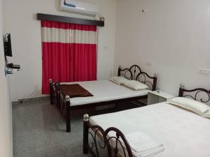 two beds in a room with a red curtain at Banpalashi Inn in Jhārgrām