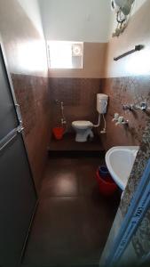 a small bathroom with a toilet and a sink at Banpalashi Inn in Jhārgrām