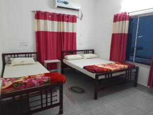 two beds in a room with red and white curtains at Banpalashi Inn in Jhārgrām