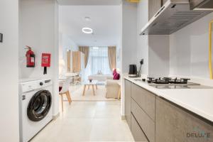 a white kitchen with a washer and dryer in it at Romantic Studio in Pantheon Elysee JVC by Deluxe Holiday Homes in Dubai
