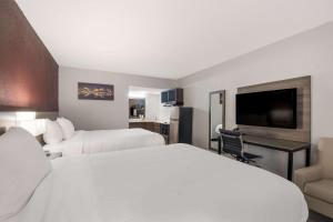 a hotel room with two beds and a flat screen tv at Suburban Studios in Cleveland