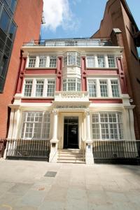 a large red and white building with a doorway at Great St Helen Hotel in London